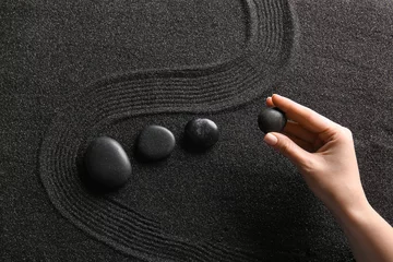Fotobehang Zen Stenen Female hand and stones on black sand with lines. Zen concept  © Pixel-Shot