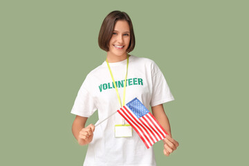 Young female volunteer with USA flag on green background