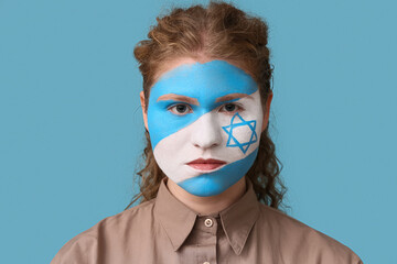 Young woman with painted flag of Israel on her face against blue background, closeup. International...