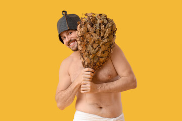 Handsome man with sauna whisk on yellow background