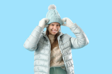 Happy young woman in winter clothes on blue background