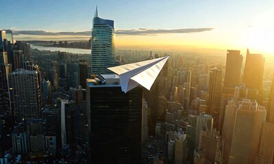 A paper airplane soaring over a city skyline at sunset.