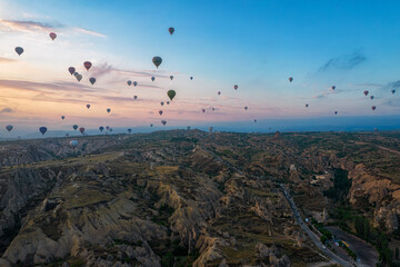 Aerial view of sunrise in Cappadocia valley with lots of balloons in the air