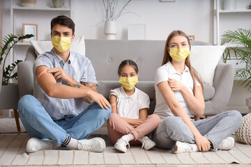 Family in masks with medical patches after vaccination sitting on floor at home