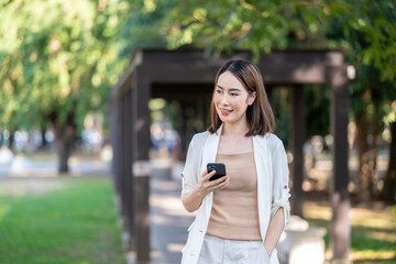 A woman is walking in a park with a cell phone in her hand