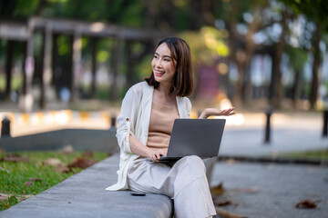 A woman is sitting on a bench with a laptop in front of her