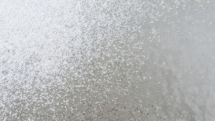Sparkling silver glitter covering a smooth surface in a creative workspace during daylight hours