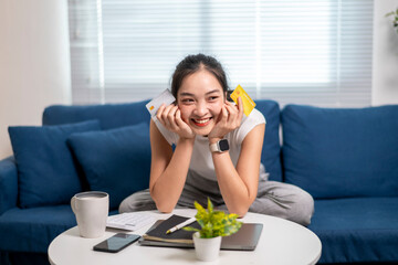 A woman is sitting on a couch with a laptop and a cell phone in front of her