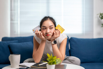 A woman is sitting on a couch with two credit cards in her hands