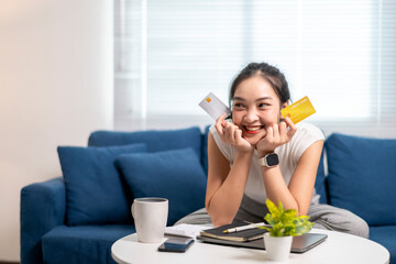 A woman is sitting on a couch with a yellow credit card in her hand