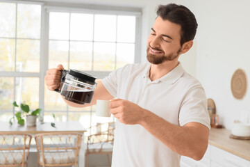 Morning of handsome man pouring coffee into cup in kitchen