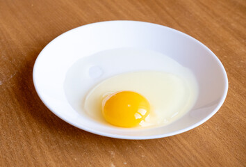 Raw egg in a plate. Egg yolk.