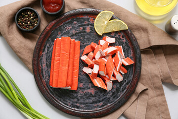 Plate with tasty crab sticks, slices of lemon and green onion on grey background © Pixel-Shot