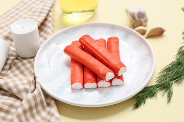 Plate with tasty crab sticks, garlic and dill on yellow background © Pixel-Shot
