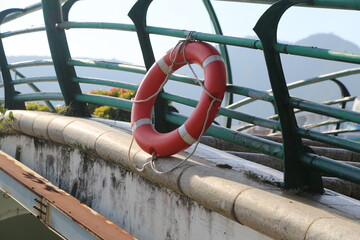 The red and white life ring is hung on the green metal guardrail of an old bridge, overlooking the...