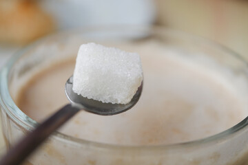 A Sugar Cube Delicately Being Added to a Warm Cup of Coffee, Enhancing the Experience