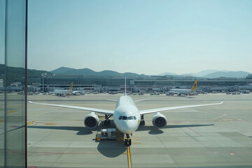 Airplane at the gate with a panoramic view of other planes taxiing in the distance. Copyspace at the top. Natural daylight. Expansive airport terminal and airfield background.