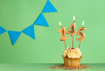 Birthday cupcake with number 145 candle - Green background with blue pennants.