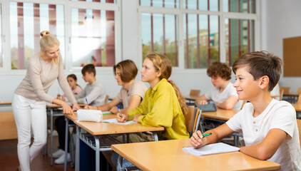 Portrait of diligent schoolboy who writing exercises at lesson in secondary school