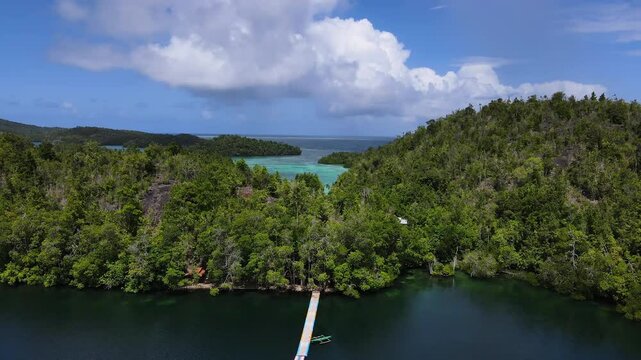 A Jetty Leading to a Boat and the Vibrant Turquoise Waters of Matano Lake, Surrounded by Lush Green Hills, in Sulawesi, Indonesia - Drone Flying Forward