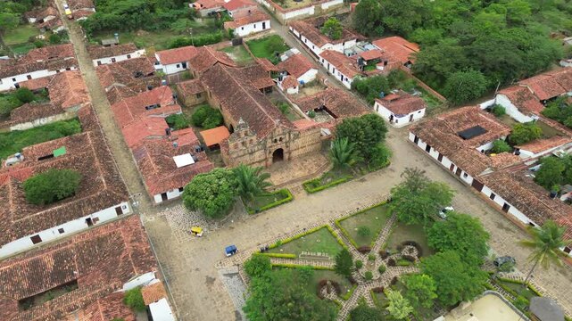 Drone approach over church at city center of Guane village, Colombia, with cobblestone streets and lush greenery