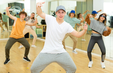 Teens training hip-hop dance moves during group rehearsal in studio.