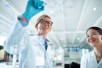 Women, scientist and mentor with formula on glass wall at laboratory for teamwork, collaboration or...