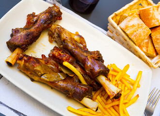 Tasty lamb meat on bone baked in oven with side dish of golden french fries..