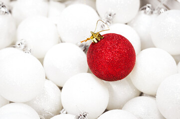 Close-up of a red Christmas ball on the background of white balls. Conceptualization of Christmas and personality differences