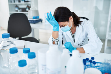 Ppe, scientist and stress as headache in science lab as frustrated, depressed or overworked. Female...