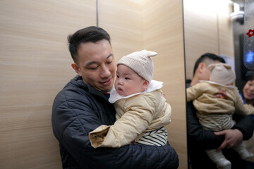 A Chinese family's father and 6-month-old boy ride in an elevator on a cold winter day in Pudong New Area, Shanghai, China.