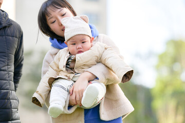 A 6-month-old boy plays with his mother and father, a Chinese family, on a cold winter day in a...