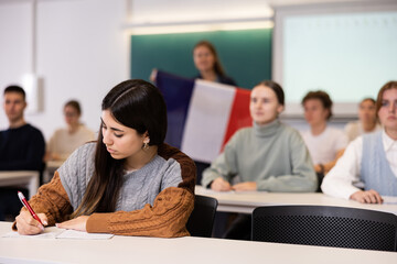 Geography lesson in school class - teacher talks about France, holding a flag in his hands