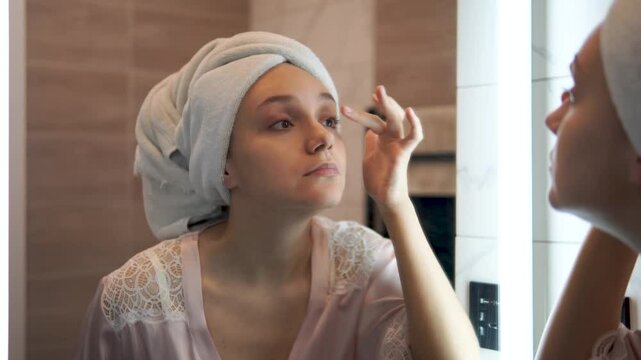 Young woman applies facial Cleaner for skin wash. girl washing face in morning in bathroom. Self Care morning bathroom routine woman portrait reflection in mirror.