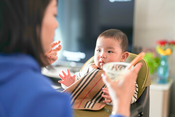 A 6-month-old boy is fed baby food by his mother from a Chinese family on a cold winter day in an...