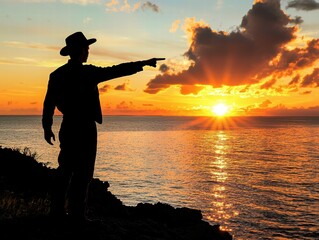 Fototapeta premium Silhouette of a Man Pointing at a Vibrant Sunset Over the Ocean