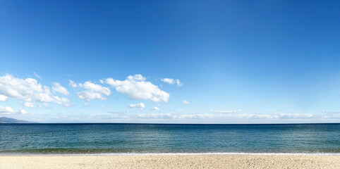 透き通った青い空に一面に広がる海と砂浜のパノラマ写真