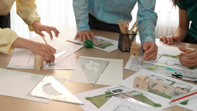 A video of architect use measurement tools and pencil to measure blueprint. Architect design house construction on a table at studio, with architectural plan scattered around. Focus hand. Delineation.
