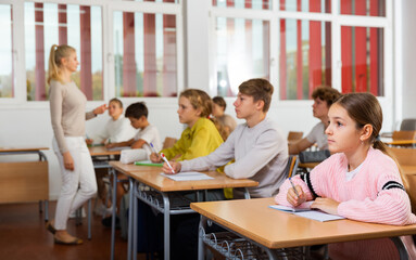 Young boys and girls studying in classroom during lesson in school.