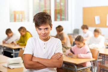 Happy boy stands in a school class against the background of classmates