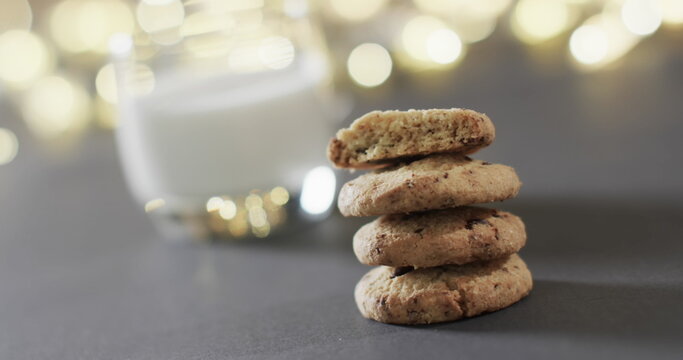 Feliz navidad text in white over christmas cookies, milk and bokeh lights