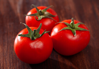 Closeup of fresh ripe tomatoes on wooden surface. Organic vegetables concept
