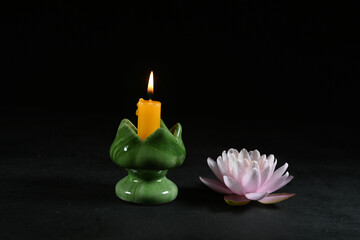 Beautiful water lily with a burning candle on a dark background
