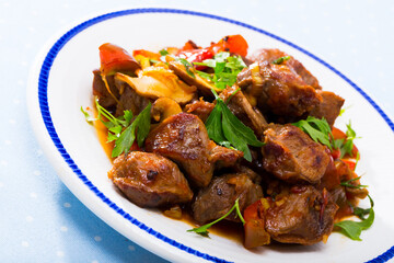 Close up of delicious fried pork with button mushroom, peppers and greens