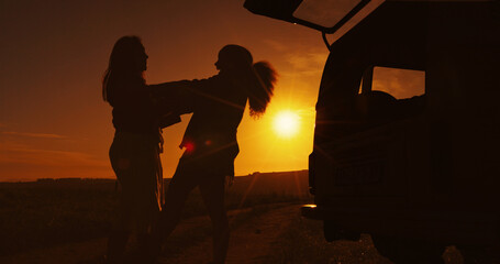 Obraz premium Road trip, silhouette and sunset with friends outdoor together for holiday, travel or vacation. Carry, countryside and vehicle with people in dark nature park for adventure, camping or journey