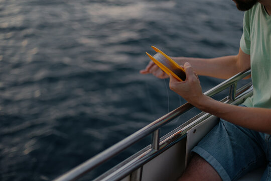 Adult caucasian male fishing on boat at sea with handline
