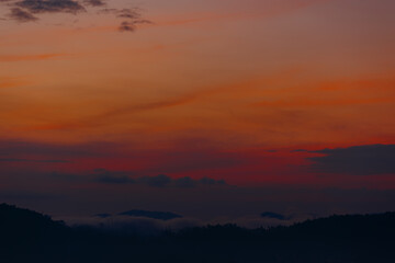 Vibrant orange and red sunset over misty hills