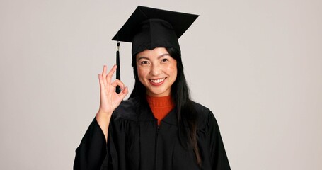 Ok, graduation and smile with portrait of asian woman in studio for success, college degree or...