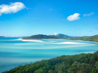 Whitehaven Beach a large body of water with mountains and trees on a sunny day on Whitsunday Island, Queensland, Australia