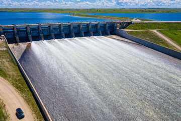 A large body of water with a dam and a car driving by